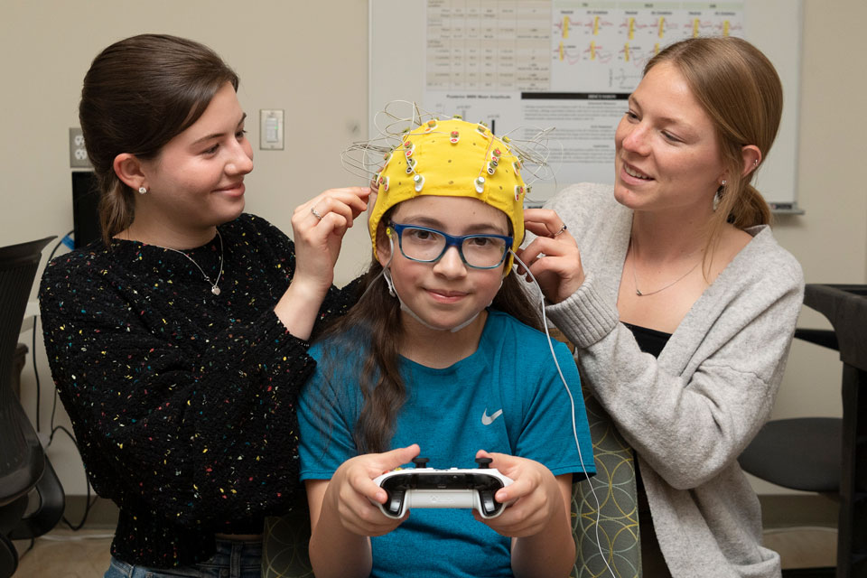 students preparing a child with an EEG cap for a session