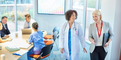a businesswoman chats with a doctor as they leave a boardroom meeting in a hospital