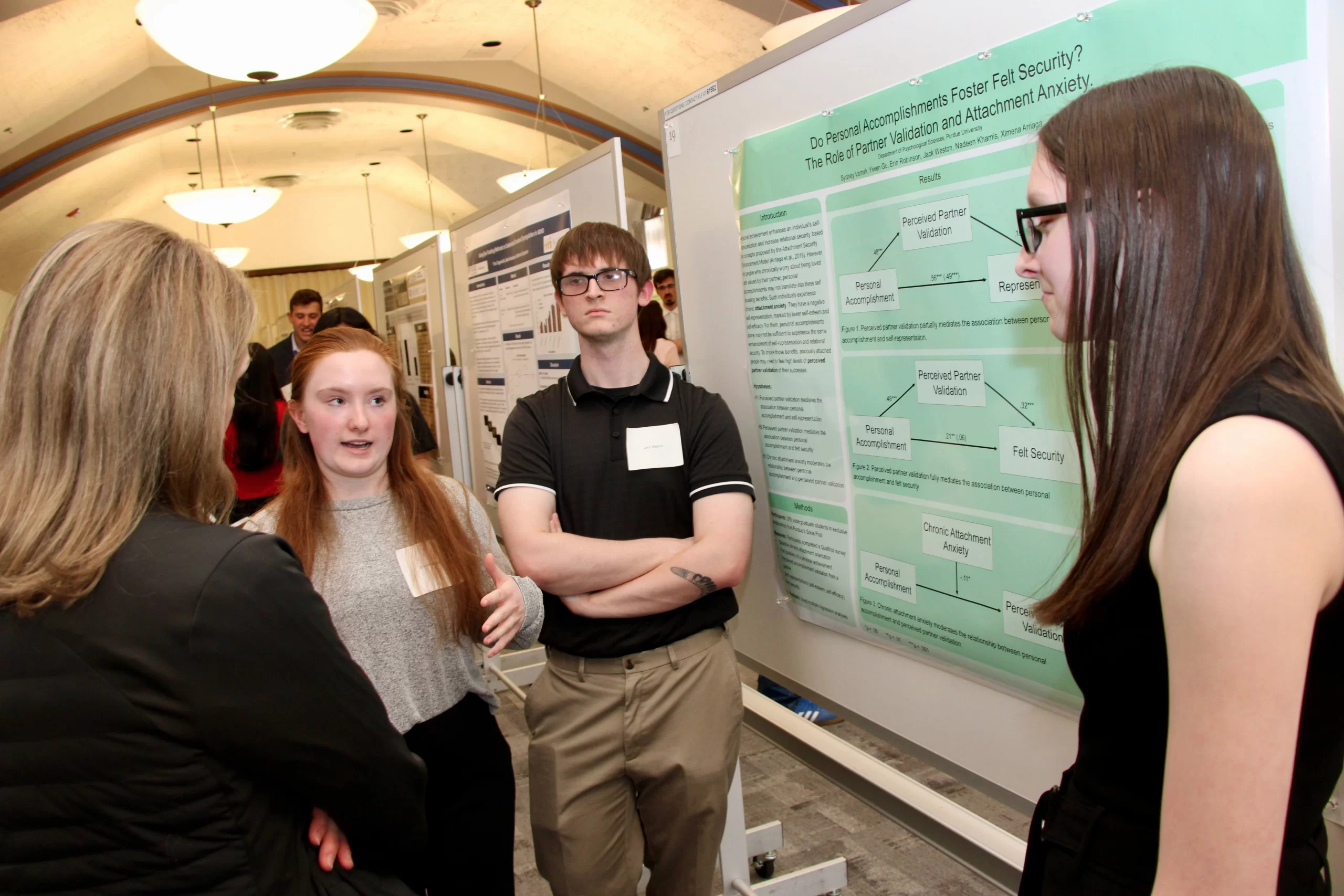 Erin and Jack discussing their poster with two other individuals.