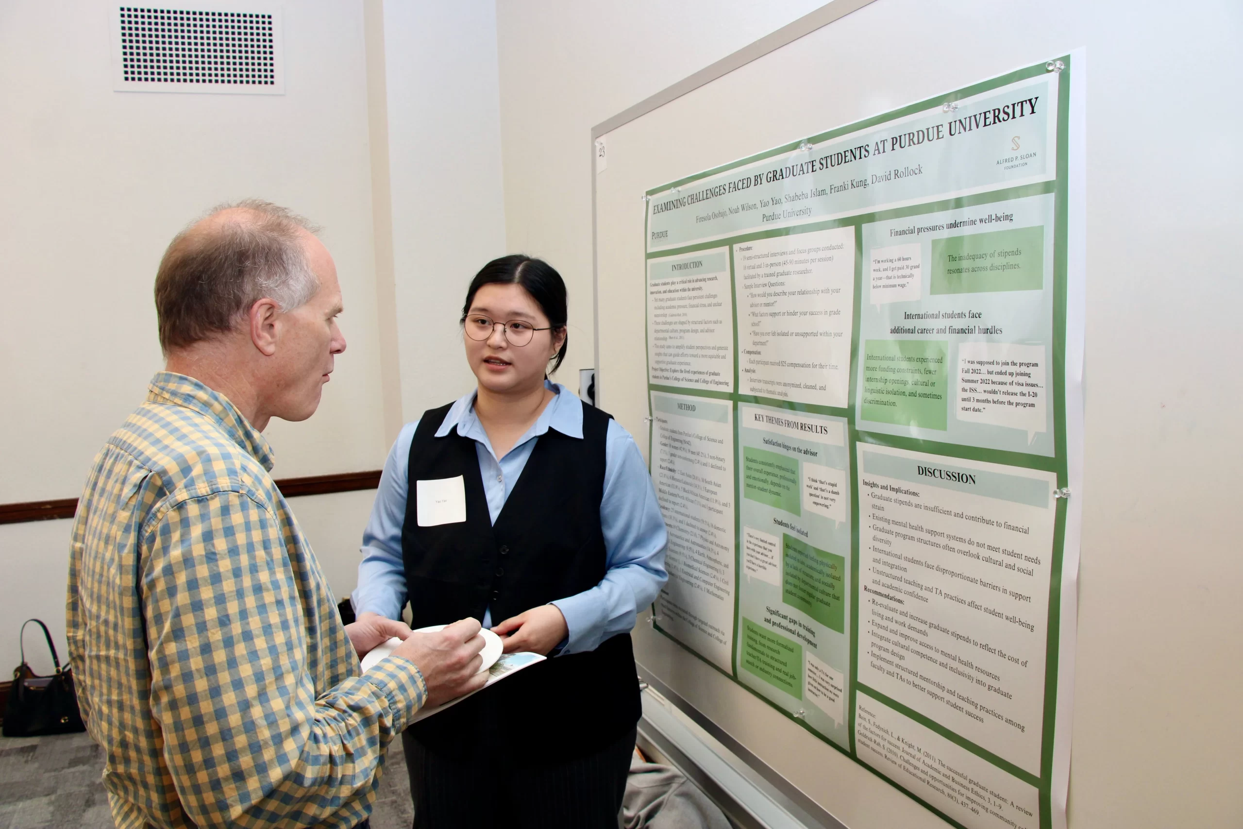 Yao Yao talking to another person about their poster.